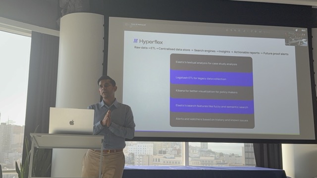 BK Bhate speaking in front of a slide showing stacked Elastic architecture layers.