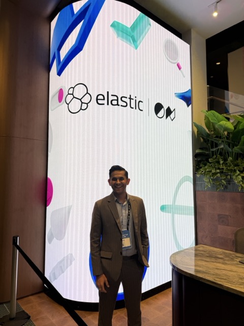 BK Bhate standing in front of large Elastic event branding.